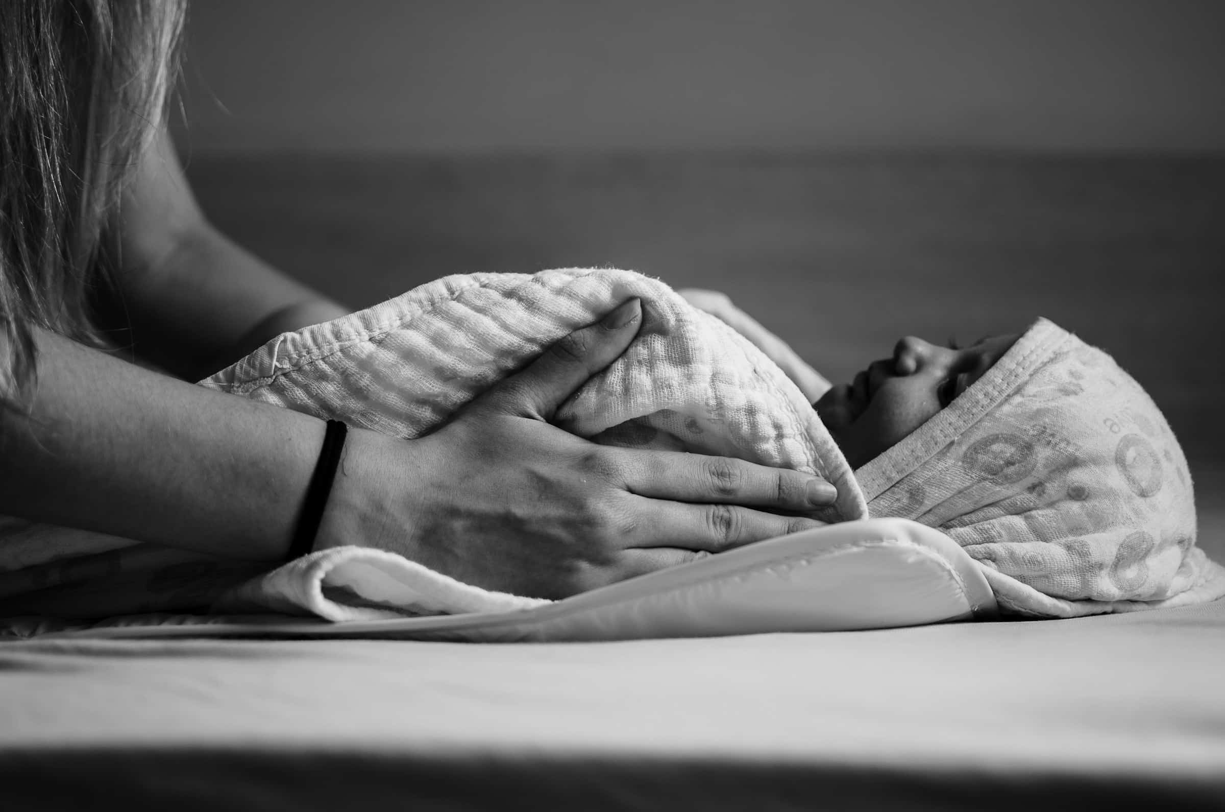 A mother resting on a bed in the fourth trimester