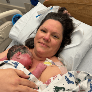 A new mother cradling her newborn in a hospital postpartum room