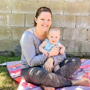 Denise sitting outside with a baby on a picnic blanket