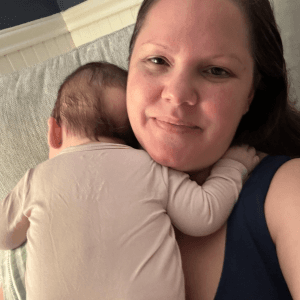 Denise with a sleeping baby resting on her shoulder